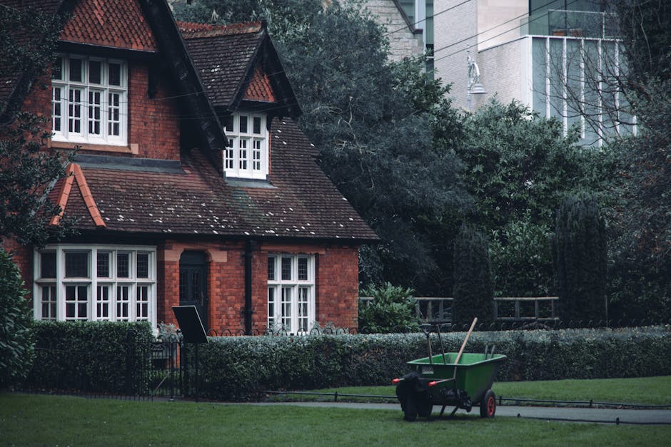 A group of multiple large purple rubbish bags made of plastic, tightly tied with red drawstrings, are placed on a grassy lawn in an open outdoor space. The background features dense green bushes and t